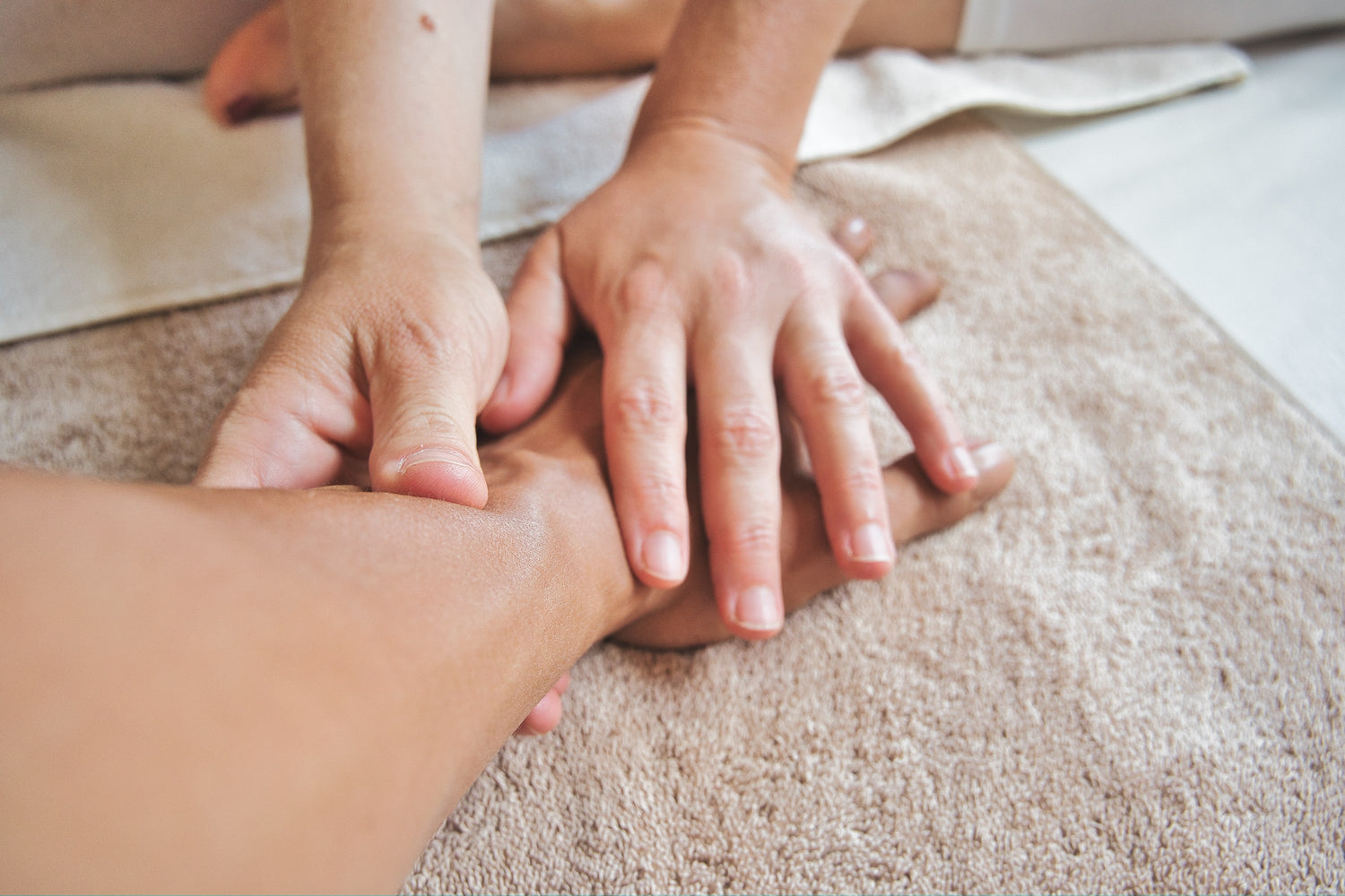 zwei Hände massieren eine Hand und den Unterarm. Therapie für Polyneuropathie.